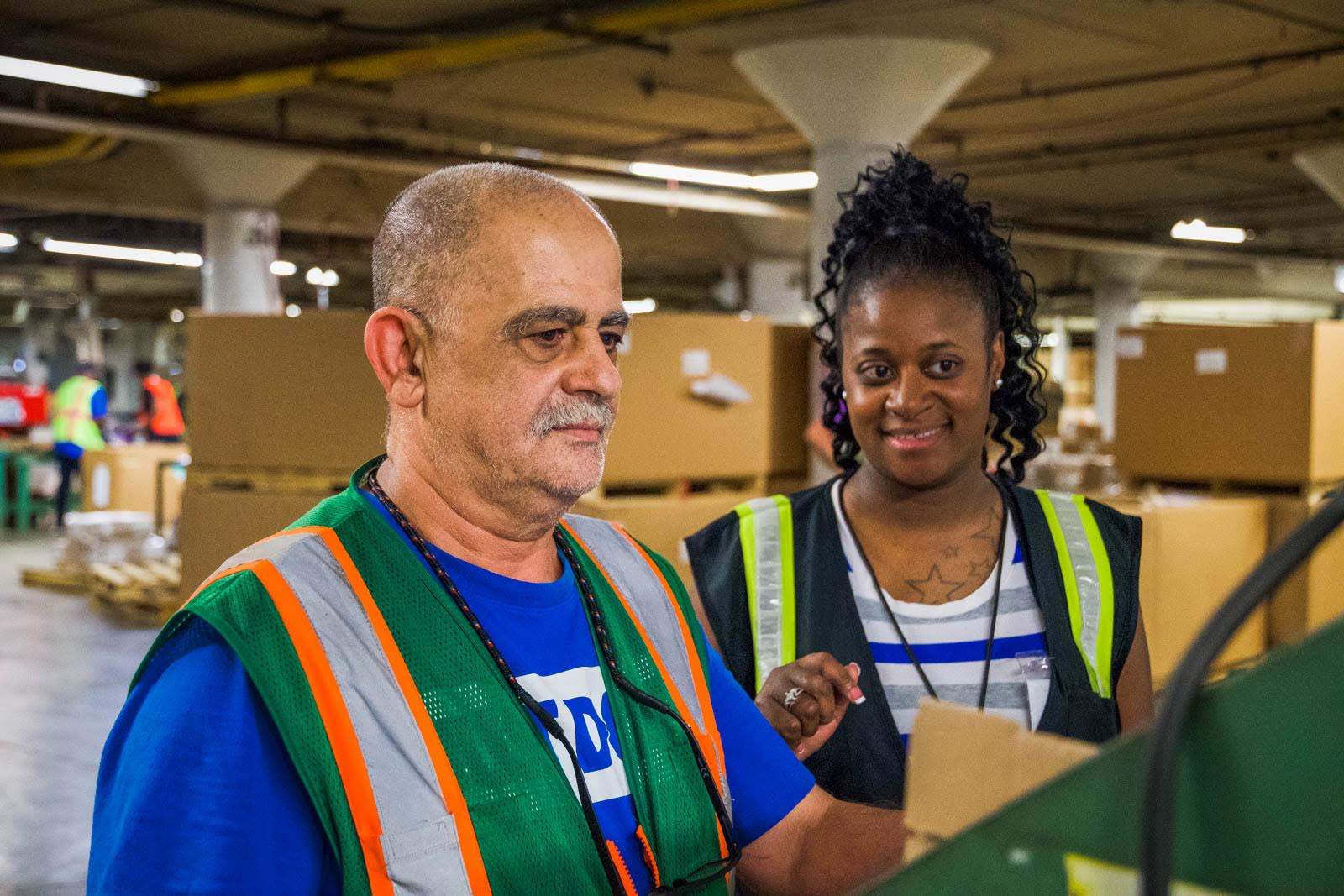 Two employees in safety vests in a warehouse